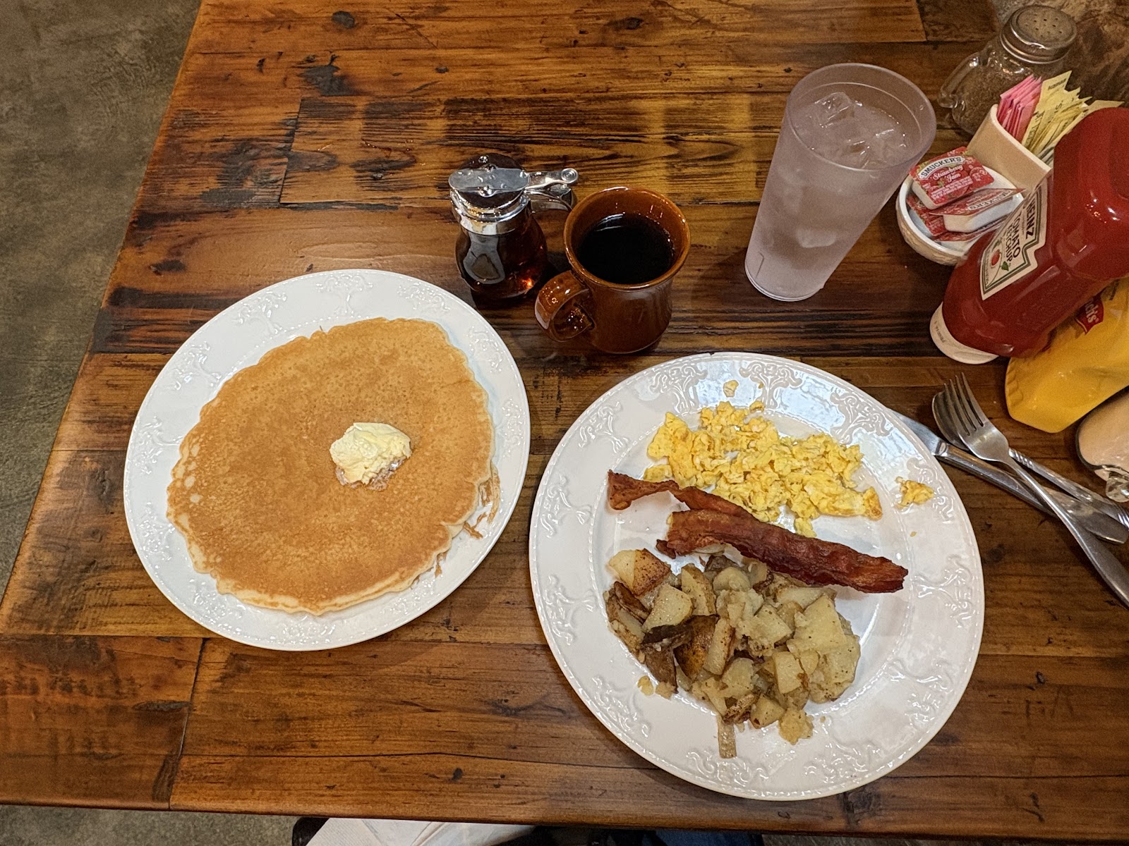 Breakfast plates, coffee, and condiments on a wooden table